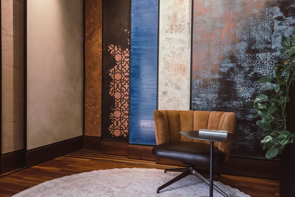 Farbentheater - Brauner Sessel vor Wand mit Dekor-Mustern