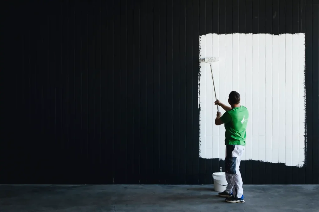 Mitarbeiter beim Ausmalen einer weißen Wand in Schwarz