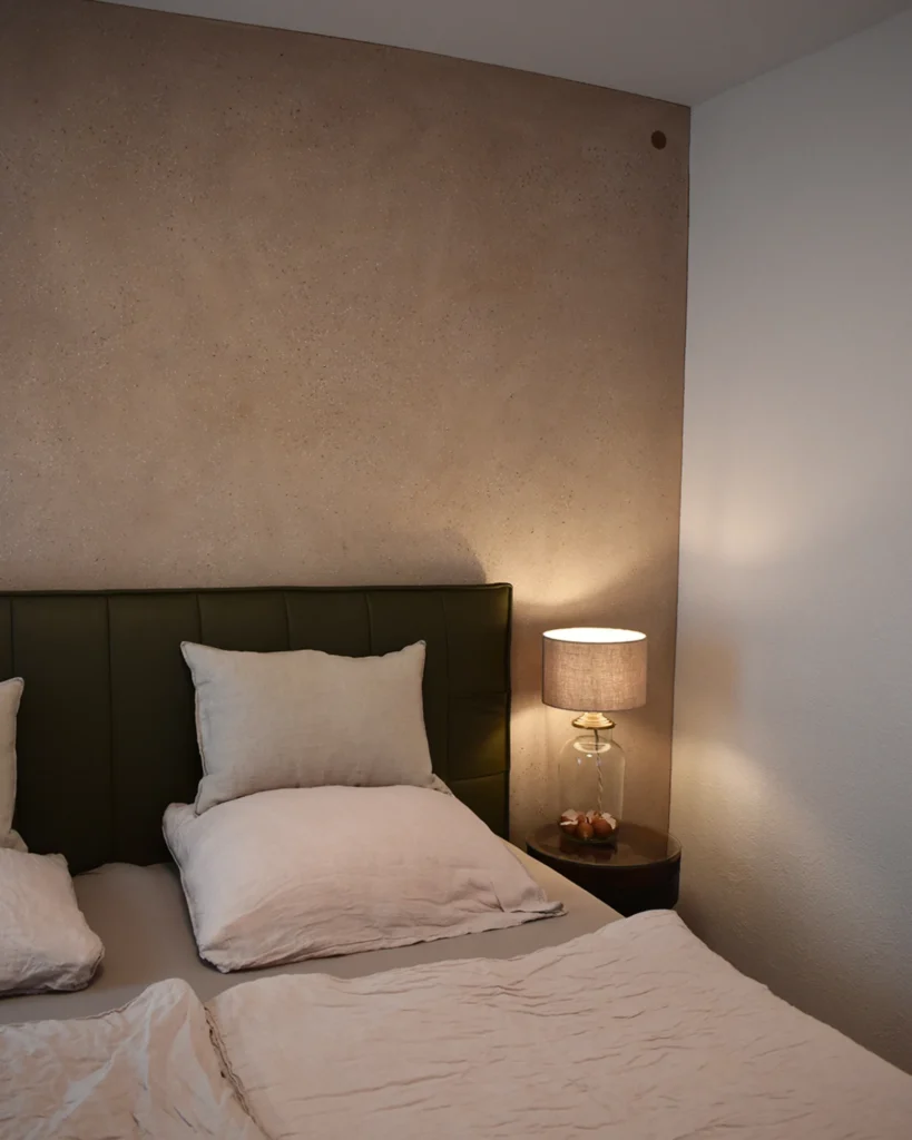 Bett mit Lampe vor einer atmenden Wand